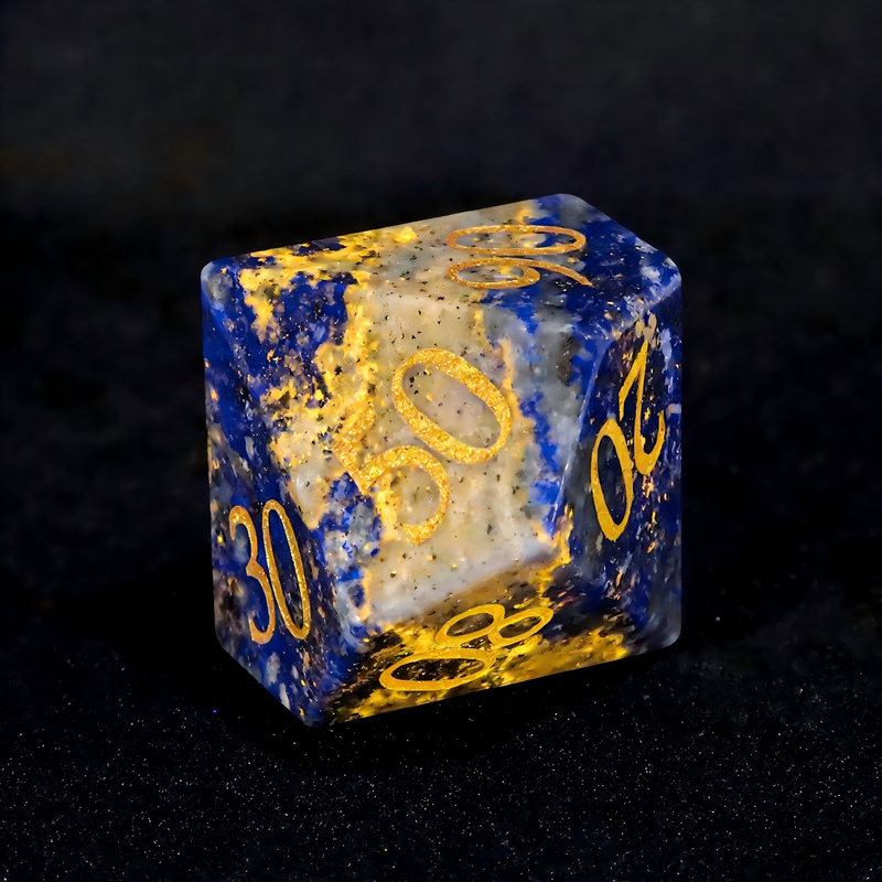 Close-up of lapis lazuli D20 die for tabletop RPG — deep celestial blue with gold pyrite flecks