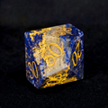 Close-up of lapis lazuli D20 die for tabletop RPG — deep celestial blue with gold pyrite flecks