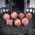 Close-up of pink cat's eye crystal D20 showing light band effect — tabletop RPG dice